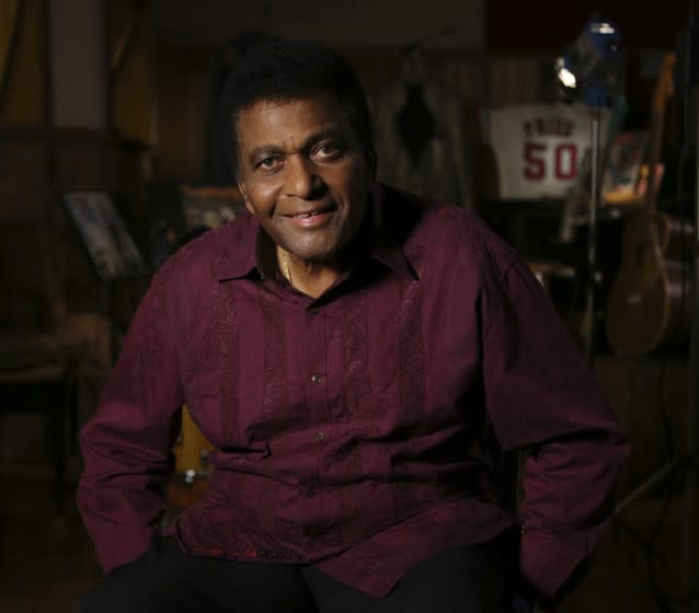 Charley Pride, decked out in a burgundy shirt, sits in his recording studio