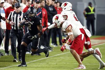 North Carolina State's Michael Allen (2) tries to avoid the tackle of Louisville's Stanquan Clark (6) and Cam'Ron Kelly, center, during the first half of an NCAA college football game in Raleigh, N.C., Friday, Sept. 29, 2023. (AP Photo/Karl B DeBlaker)