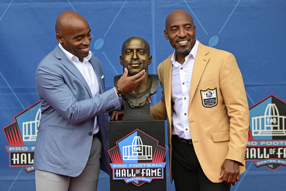 Former NFL players Ronde Barber, right, poses with his twin brother Tiki Barber and Ronde's bust during his induction into the Pro Football Hall of Fame in Canton, Ohio, Saturday, Aug. 5, 2023. (AP Photo/David Dermer)