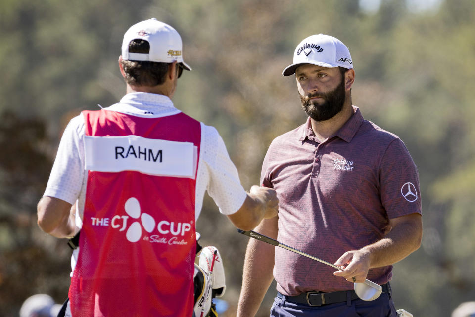 Jon Rahm, of Spain, hands a club to his caddie after putting on the first green during the final round of the CJ Cup golf tournament Sunday, Oct. 23, 2022, in Ridgeland, S.C. (AP Photo/Stephen B. Morton)