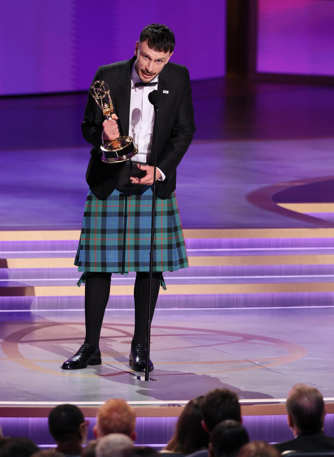 Richard Gadd, wearing a kilt, holds an Emmy and speaks into a microphone onstage