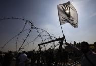 A supporter of the Muslim Brotherhood and ousted Egyptian President Mohamed Mursi shouts slogans while carrying a flag, bearing the symbol of the Rabaa gesture, in front of a barbed wire barricade outside the police academy, where Mursi's trial took place, on the outskirts of Cairo, November 4, 2013. Mursi struck a defiant tone on the first day of his trial on Monday, chanting 'Down with military rule', and calling himself the country's only 'legitimate' president. Mursi, an Islamist who was toppled by the army in July after mass protests against him, appeared angry and interrupted the session repeatedly, prompting a judge to adjourn the case. The "Rabaa" or "four" gesture is in reference to the police clearing of Rabaa al-Adawiya protest camp on August 14. The words on the flag read, "Rabaa, it's our sign of power." REUTERS/Amr Abdallah Dalsh (EGYPT - Tags: POLITICS CIVIL UNREST TPX IMAGES OF THE DAY)