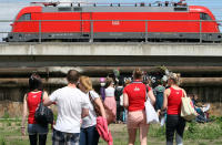 BERLIN, GERMANY - JULY 21: Attendees wait for the start of the games as a Deutsche Bahn regional train passes overhead at the second annual Hipster Olympics on July 21, 2012 in Berlin, Germany. With events such as the "Horn-Rimmed Glasses Throw," "Skinny Jeans Tug-O-War," "Vinyl Record Spinning Contest" and "Cloth Tote Sack Race," the Hipster Olympics both mocks and celebrates the Hipster subculture, which some critics claim could never be accurately defined and others that it never existed in the first place. The imprecise nature of determining what makes one a member means that the symptomatic elements of adherants to the group vary in each country, but the archetype of the version in Berlin, one of the more popular locations for those following its lifestyle, along with London and Brooklyn, includes a penchant for canvas tote bags, the carbonated yerba mate drink Club Mate, analogue film cameras, asymetrical haircuts, 80s neon fashion, and, allegedly, a heavy dose of irony. To some in Berlin, members of the hipster "movement" have replaced a former unwanted identity in gentrifying neighborhoods, the Yuppie, for targets of criticism, as landlords raise rents in the areas to which they relocate, particularly the up-and-coming neighborhood of Neukoelln. (Photo by Adam Berry/Getty Images)