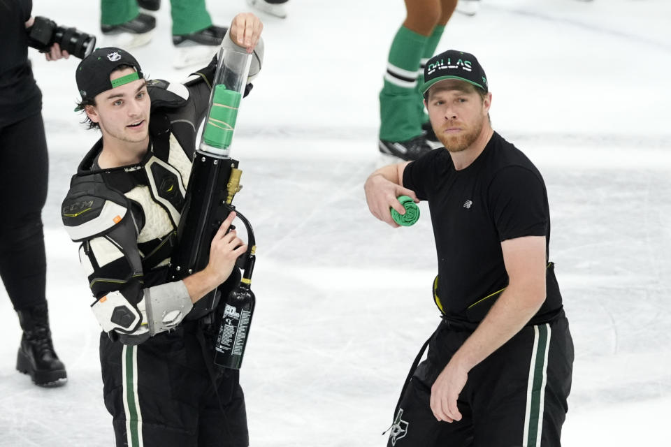 Dallas Stars' Wyatt Johnston, left, and Joe Pavelski, right, toss souvenirs to fans after the team's 2-1 shootout win in an NHL hockey game against the St. Louis Blues in Dallas, Wednesday, April 17, 2024. There is quite an age gap for the Western Conference champion Dallas Stars. Top goal scorer Wyatt Johnston is only 20-years-old while Joe Pavelski is 39. (AP Photo/Tony Gutierrez)