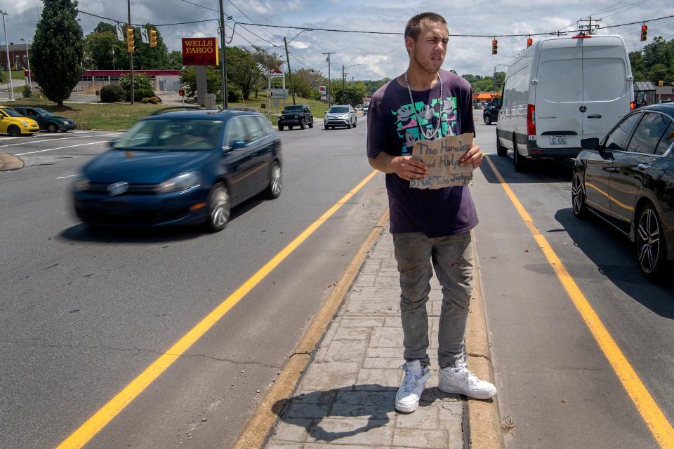 In this file photo from Asheville, N.C., Sean Alcock, who is homeless, stands in the middle of a roadway asking for help from motorists. Jacksonville's ordinance bans this type of soliciting on many roads.