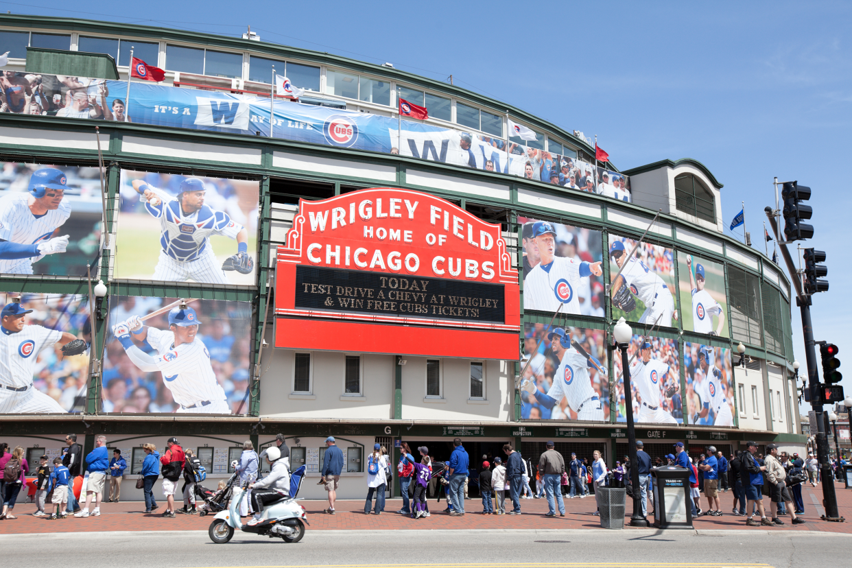 Exterior of Wrigley Field Stadium, Chicago, home of the Chicago Cubs with many people lined up on a clear late spring day