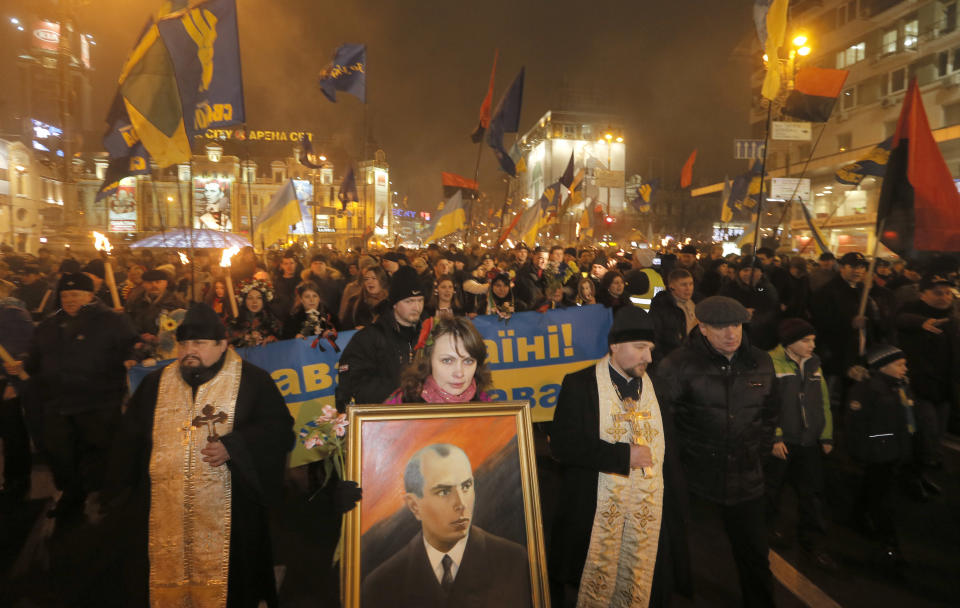 A Ukrainian nationalist carries a portrait of Stepan Bandera, founder of the Ukrainian rebel army that fought against the Soviet regime, during a rally in downtown Kiev, Ukraine, late Wednesday, Jan. 1, 2014. The rally was organized on the occasion of Bandera's birth anniversary.(AP Photo/Efrem Lukatsky)