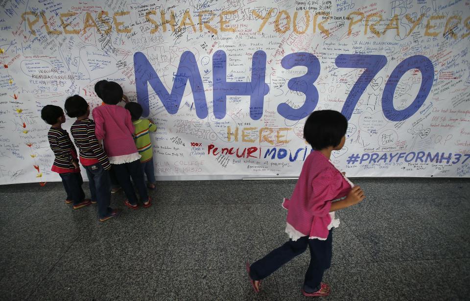 FILE - In this March 13, 2014 file photo, Children read messages and well wishes displayed for all involved with the missing Malaysia Airlines jetliner MH370 on the walls of the Kuala Lumpur International Airport in Sepang, Malaysia. Ten days after Malaysia Airlines Flight 370 disappeared with 239 people aboard, an exhaustive international search has produced no sign of the Boeing 777, raising an unsettling question: What if the airplane is never found? (AP Photo/Wong Maye-E, File)