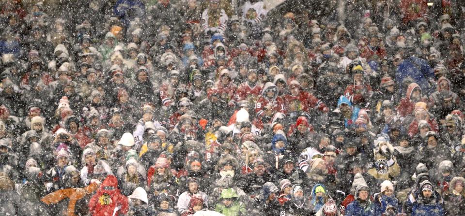 Hockey fans watch the Chicago Blackhawks face the Pittsburgh Penguins as snow falls during the first period of an NHL Stadium Series hockey game at Soldier Field on Saturday, March 1, 2014, in Chicago. (AP Photo/Charles Rex Arbogast)