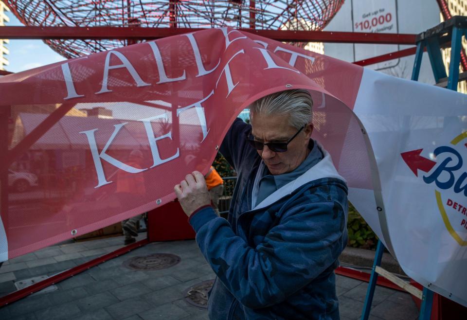 Kevin Andrews, 62, of Macomb Township, a maintenance supervisor for The Salvation Army Great Lakes Division, walks under a giant banner early morning during the installation of the "World's Tallest Red Kettle" at Cadillac Square in Detroit on Friday, Nov. 10, 2023.