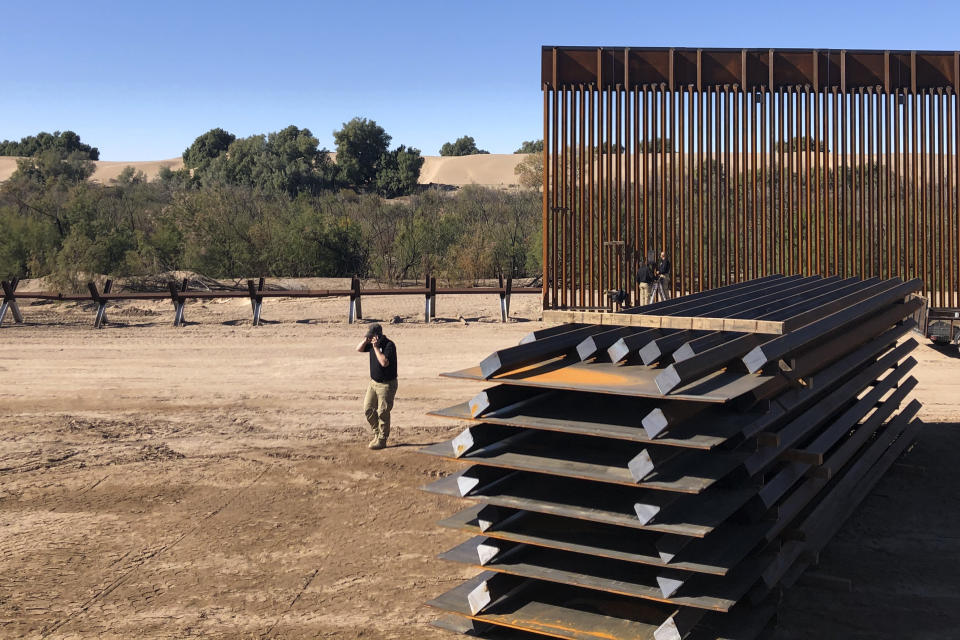 A man passes new border wall sections, right, as they replace the old fencing, left, Friday, Jan. 10, 2020, near Yuma, Arizona. Top Trump administration officials will visit South Texas five days before Election Day to announce they have completed 400 miles of U.S.-Mexico border wall, attempting to show progress on perhaps the president's best-known campaign promise four years ago. But most of the wall went up in areas that already had smaller barriers. (AP Photo/Elliot Spagat)