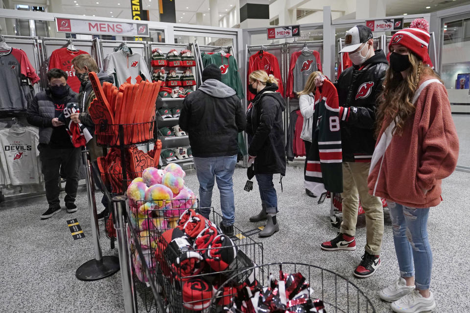 Fans line cup to pay for their purchases at a New Jersey Devils team store before an NHL game between the Devils and the New York Islanders, Tuesday, March 2, 2021, in Newark, N.J. It was the first time fans were allowed in the Prudential Center under New Jersey's more relaxed COVID-19 rules. (AP Photo/Kathy Willens)