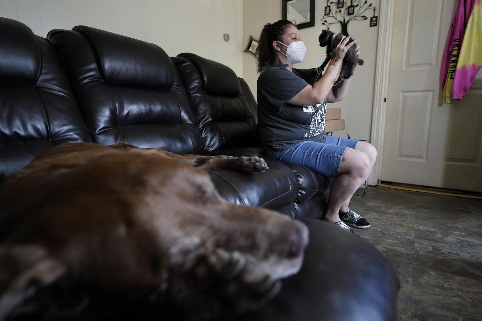 Roxanne Schaefer, of West Warwick, R.I., lifts a kitten while sitting near a family dog, a 15-year-old Labrador mix named Marvel, Tuesday, July 27, 2021, at her apartment, in West Warwick. Schaefer, who is months behind on rent, is bracing for the end to a CDC federal moratorium Saturday, July 31, 2021, a move that could result in millions of people being evicted just as the highly contagious delta variant of the coronavirus is rapidly spreading. (AP Photo/Steven Senne)