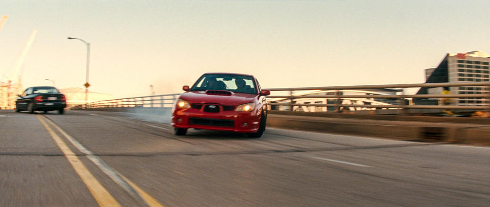 A red sports car racing down a road swerving around another car