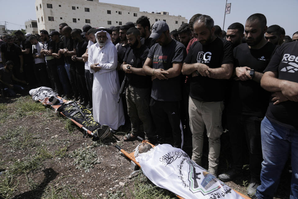 Mourners pray at the funeral for three people, draped in Fatah and Islamic Jihad militant flags, killed in an Israeli military operation, in Jenin refugee camp in the West Bank city of Jenin, Friday, July 5, 2024. The Israeli military said Friday it was conducting counterterrorism activity that included an airstrike in the area of the West Bank city of Jenin. Palestinian authorities said five people were killed. (AP Photo/Majdi Mohammed)