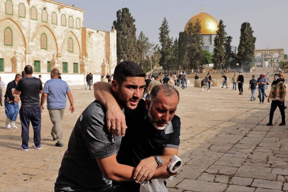 A Palestinian man helps a wounded fellow protester amid clashes with Israeli security forces at Jerusalem’s Al-Aqsa mosque compoundAFP via Getty Images