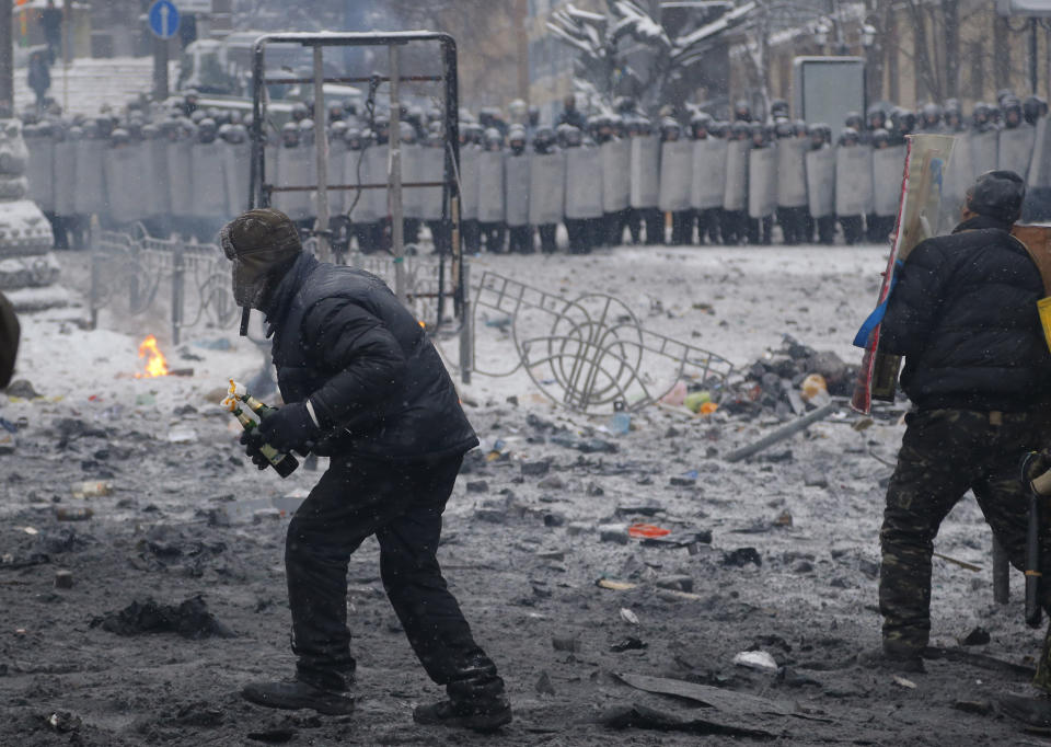 A protester, left, prepares to throw a Molotov cocktail during clashes with police in central Kiev, Ukraine, early Wednesday, Jan. 22, 2014. Two people have died in clashes between protesters and police in the Ukrainian capital Wednesday, according to medics on the site, in a development that will likely escalate Ukraine’s two month-long political crisis. (AP Photo/Sergei Grits)