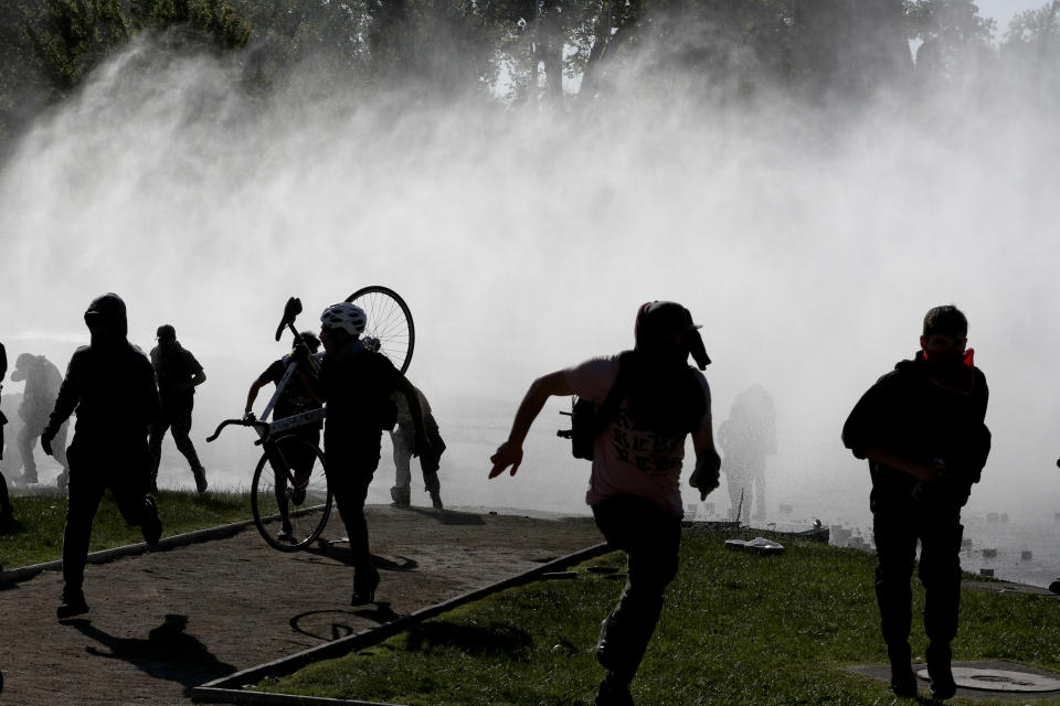 Demonstrators run from tear gas launched by police as a state of emergency remains in effect in Santiago, Chile, Sunday, Oct. 20, 2019. Protests in the country have spilled over into a new day, even after President Sebastian Pinera cancelled the subway fare hike that prompted massive and violent demonstrations. (Photo: Esteban Felix/AP)