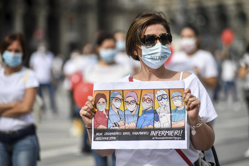 Nurses belonging to Movimento Nazionale Infermieri (National Movement of Nurses union) practice social distancing as they gather to protest for better working conditions following the coronavirus pandemic which hit Italy in the past months, in Milan's Piazza Duomo square, Italy, Monday, June 15, 2020. Writing on sign reads in Italian "Don't call us heroes, call us nurses!". (Claudio Furlan/LaPresse via AP)