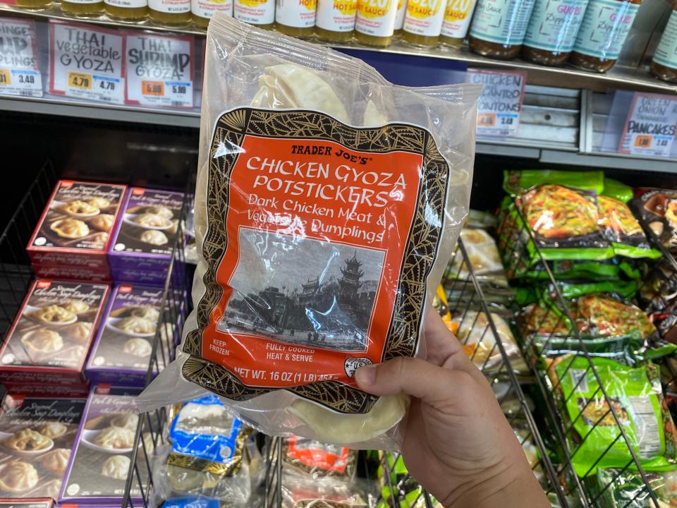 hand holding bag of chicken gyoza potstickers in the freezer aisle at trader joes