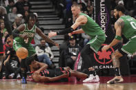 Toronto Raptors forward Thaddeus Young (21) tries to make a pass from the floor as Boston Celtics guard Jrue Holiday (4) and center Kristaps Porzingis, second from right, watch during second-half NBA basketball game action in Toronto, Monday Jan. 15, 2024. (Nathan Denette/The Canadian Press via AP)