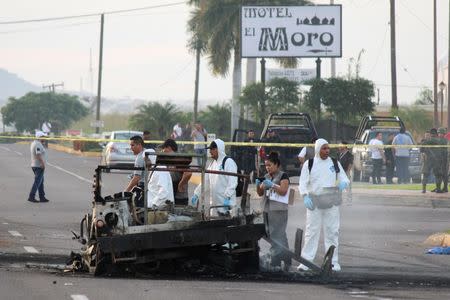 Forensic technicians stand at a crime scene next to the burnt wreckage of a military vehicle, after what local media said was an ambush by gunman on a military convoy to free an injured fellow gunman from an ambulance, in Culiacan, in Sinaloa state, Mexico, September 30, 2016. REUTERS/Jesus Bustamante