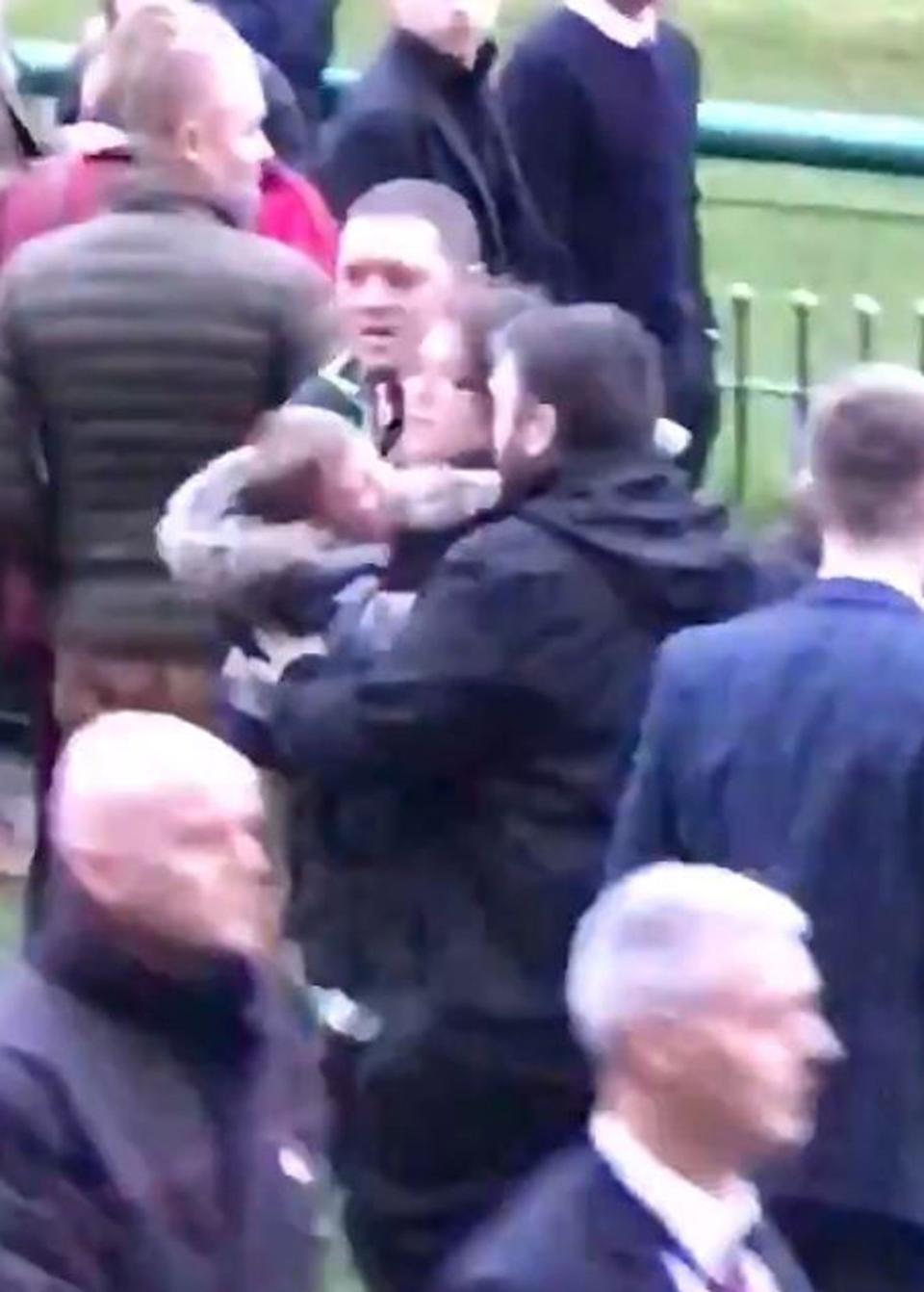 A woman clutching a small child had to be led to safety after appearing to get caught up in the fighting (Oliver Hodgson/Twitter/PA)