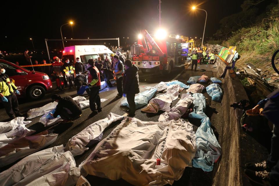 Bodies are covered at the scene of a crash where a bus collided with a car on a highway in Taipei, Taiwan, Monday, Feb. 13, 2017. A tour bus has flipped over on a highway near Taiwan's capital, killing over 30 people and trapping many others, officials said. (AP Photo)