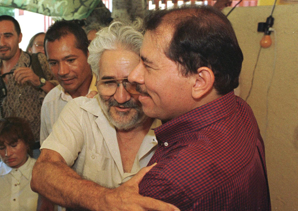 FILE - In this Sept. 21, 1998 file photo, former Sandinista guerrilla leader Eden Pastora embraces former Nicaraguan President and Sandinista National Liberation Front leader Daniel Ortega, in Managua, Nicaragua. Pastora, one of the most mercurial, charismatic figures of Central America’s revolutionary upheavals, has died. His son Alvaro Pastora said Tuesday, June 16, 2020, that he died at Managua’s Military Hospital of respiratory failure. (AP Photo/Anita Baca, File)