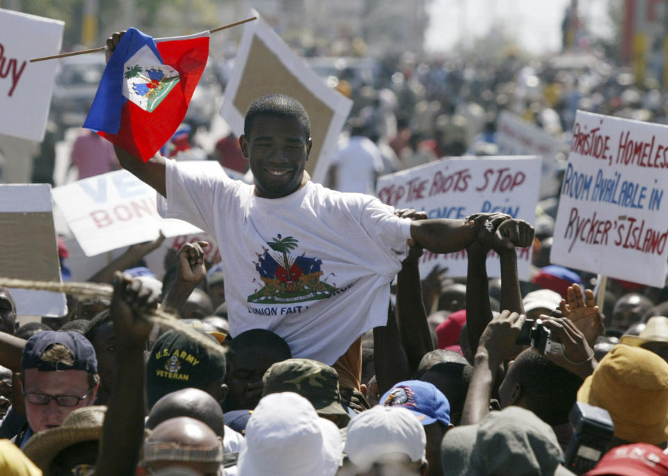 FILE - Guy Philippe, who led the rebellion against former President Jean-Bertrand Aristide, is greeted by supporters during a march of thousands in Port-au-Prince, Haiti, March 7, 2004. In December 2001, then a police official, Philippe attacked the National Palace in an attempted coup which led Haitian President Jean-Bertrand Aristide to call on the gangsters to rise from the slums. (AP Photo/Ricardo Mazalan, File)