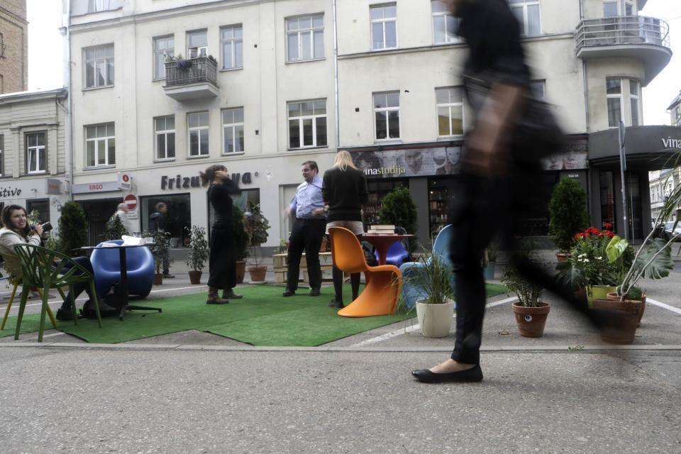 A woman walks past people participating in a PARK(ing) Day event in Riga, September 20, 2013. (REUTERS/Ints Kalnins)