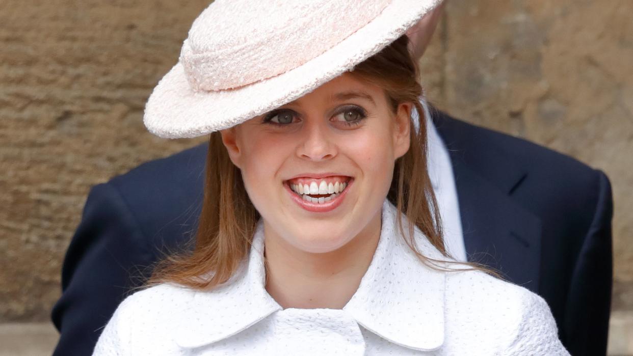 Princess Beatrice smiling in a white coat dress