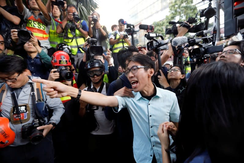 A pro-democratic winning candidate at district council local elections argues with police officers as they walk towards the campus of the Polytechnic University (PolyU) in Hong Kong