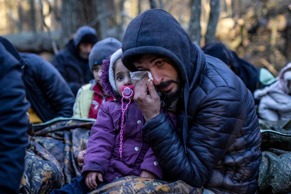 A man holds a child as members of the Kurdish family Iraq wait for the border guard patrol near Narewka (AFP via Getty Images)