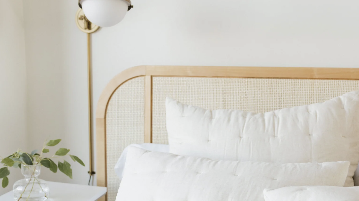 a bed with white sheets and an off white quilt