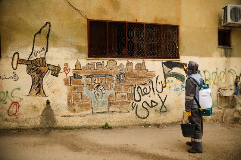 A worker sanitizes the exterior of a house in al-Fari'ah refugee camp in the Israeli-occupied West Bank