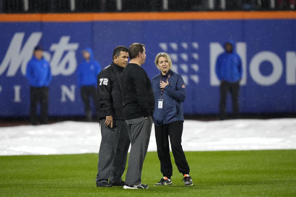 Officials stand on the field after grounds crew members pulled the tarp off of the infield during a rain delay of a baseball game between the New York Mets and the Miami Marlins early Friday, Sept. 29, 2023, in New York. (AP Photo/Frank Franklin II)