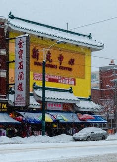 A sign is seen for &#39;all day dim sum&#39; on the front of a Chinese restaurant amid other signage while it is snowing outside.
