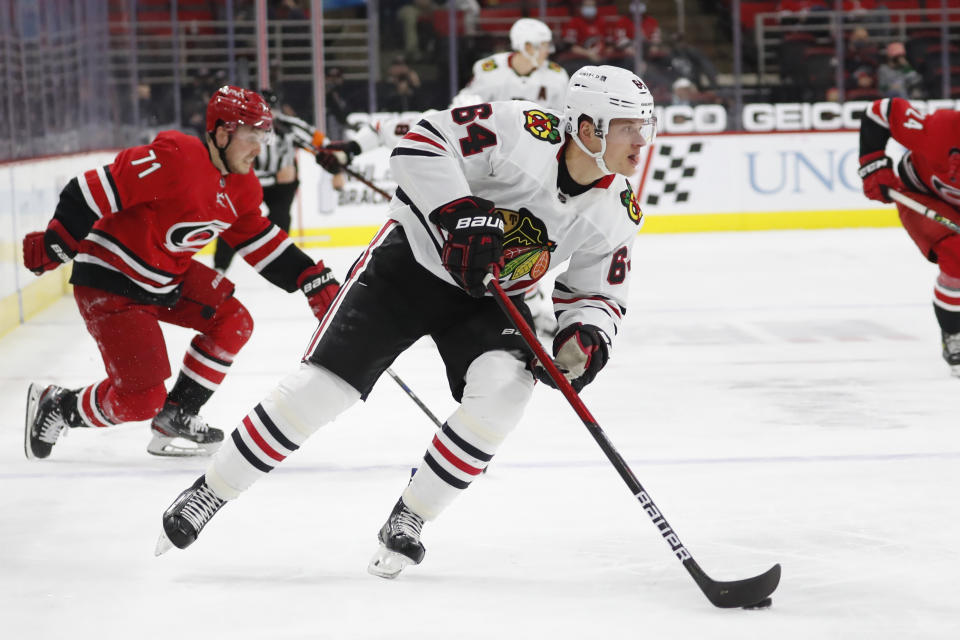 Chicago Blackhawks' David Kampf (64) drives the puck toward the net after making it past Carolina Hurricanes' Jesper Fast (71) during the first period of an NHL hockey game in Raleigh, N.C., Thursday, May 6, 2021. (AP Photo/Karl B DeBlaker)