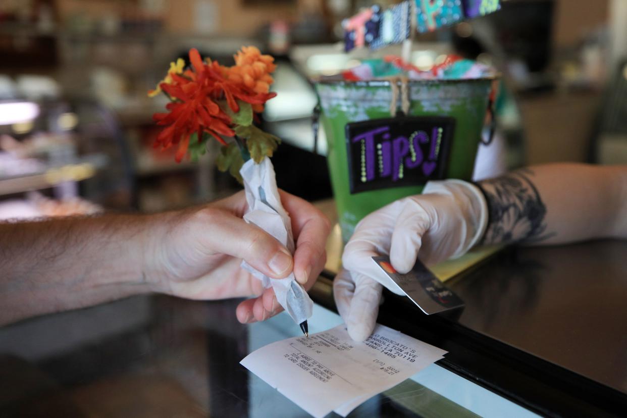 A patron uses a pen wrapped in paper to sign a credit card receipt