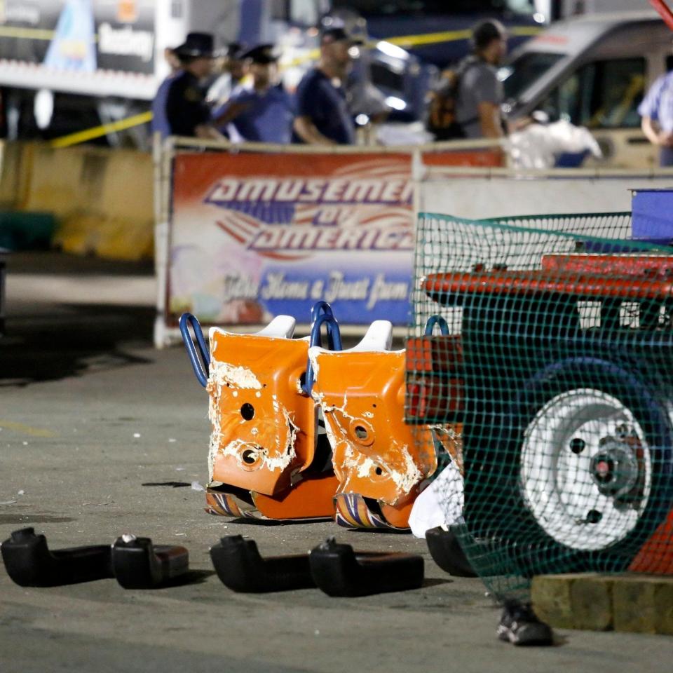 Authorities stand near damaged chairs of the Fire Ball amusement ride at the Ohio State Fair - Credit: AP