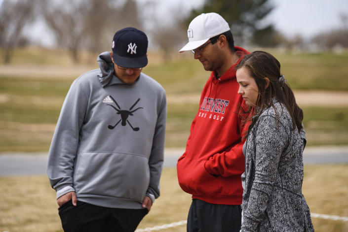 University of the Southwest golf players from left, Phillip Lopez, Jonny Flores and Halie Cruz visit the site of a memorial erected for the victims of the USW golf teams car wreck Thursday, March 17, 2022 at the Rockwind Community Links in Hobbs, N.M. (Eli Hartman/Odessa American via AP)