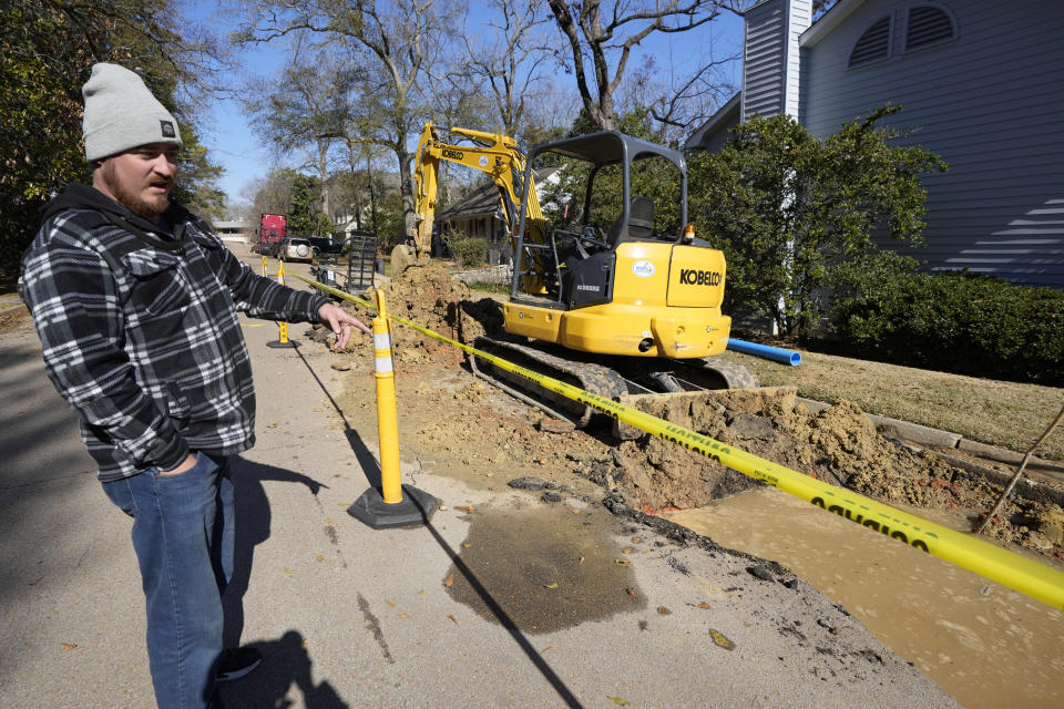 Local resident Andrew McQuirk surveys the waterline excavation a repair crew is draining in downtown Jackson, Miss., Friday, Jan. 19, 2024, after a break forced repairs. Law enforcement agencies are investigating whether social media rumors about a potential water outage prompted people to quickly fill bathtubs with tap water in Mississippi's capital during a cold snap and cause a drop in pressure that temporarily made faucets run dry for thousands of customers on the city's long-troubled system. (AP Photo/Rogelio V. Solis)