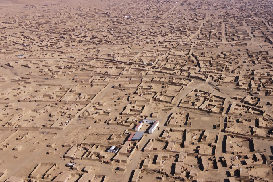 People gather near a makeshift clinic at a sprawling settlement of mud brick huts housing those displaced by war and drought, near Herat, Afghanistan, Dec. 12, 2021. Malnutrition stalks the most vulnerable, and aid groups say more than half the population faces acute food shortages. (AP Photo/Mstyslav Chernov)