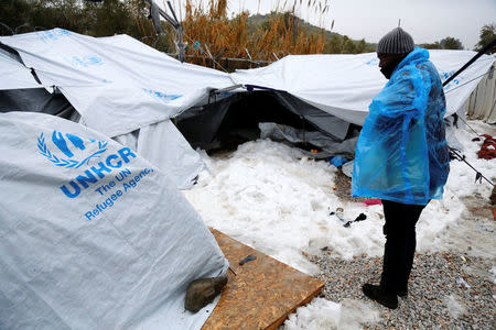 A migrant is covered with a plastic cover to protect from low temperatures as snow lays next to tents provided by the UNHCR at the refugee camp of Moria on the Greek island of Lesbos, January 10, 2017. Petros Tsakmakis/Intimenews via REUTERS