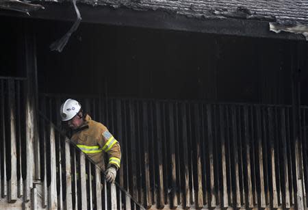 A firefighter climbs a staircase to the second floor of the charred remains of the Mariner's Cove Inn in Point Pleasant Beach, New Jersey, March 21, 2014. REUTERS/Charles Mostoller