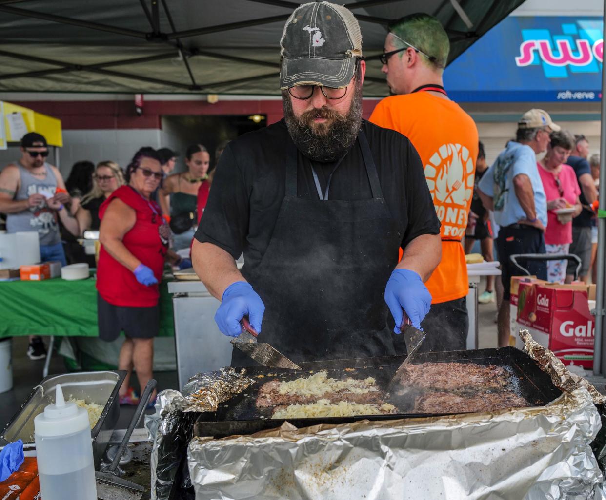 Marc Wolbert, from Ozone's Fire Food, prepares and cooks 24 olive burgers at a time at the Olive Burger Festival at Jackson Field Saturday, June 24, 2023.