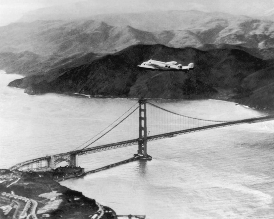 A plane piloted by American aviator Amelia Earhart and Fred Noonan flies over the Golden Gate bridge in Oakland, California, at the start of a planned round-the-world flight on March 17, 1937.