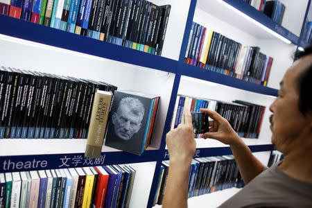 A man takes pictures of a collection of writings by Samuel Beckett at the Cambridge University Press (CUP) stall at the Beijing International Book Fair in Beijing, China, August 23, 2017. REUTERS/Thomas Peter