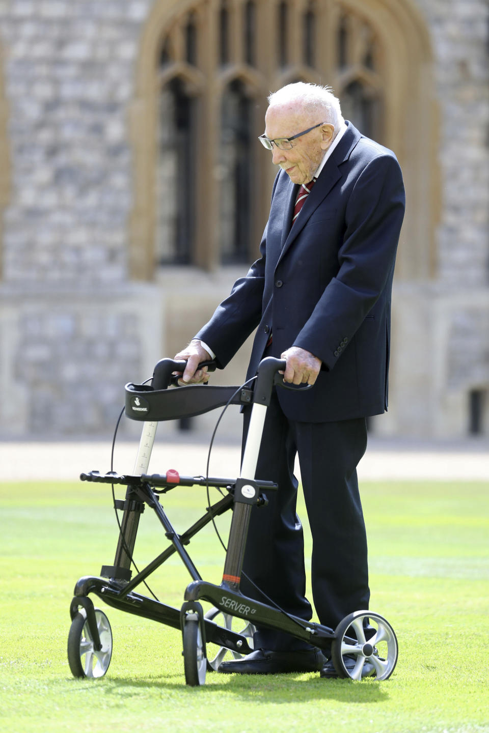 Captain Sir Thomas Moore arrives to receive his knighthood from Britain's Queen Elizabeth, during a ceremony at Windsor Castle in Windsor, England, Friday, July 17, 2020. Captain Sir Tom raised almost £33 million for health service charities by walking laps of his Bedfordshire garden. (Chris Jackson/Pool Photo via AP)